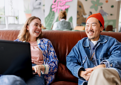 Man and woman sat on the sofa, laughing