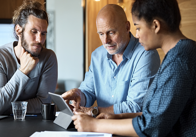 two men and a women looking at an iPad