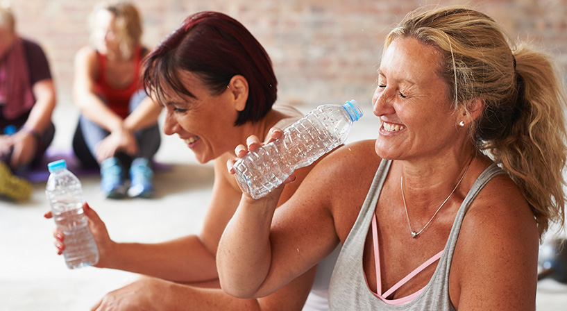 women laughing drinking water after exercise class