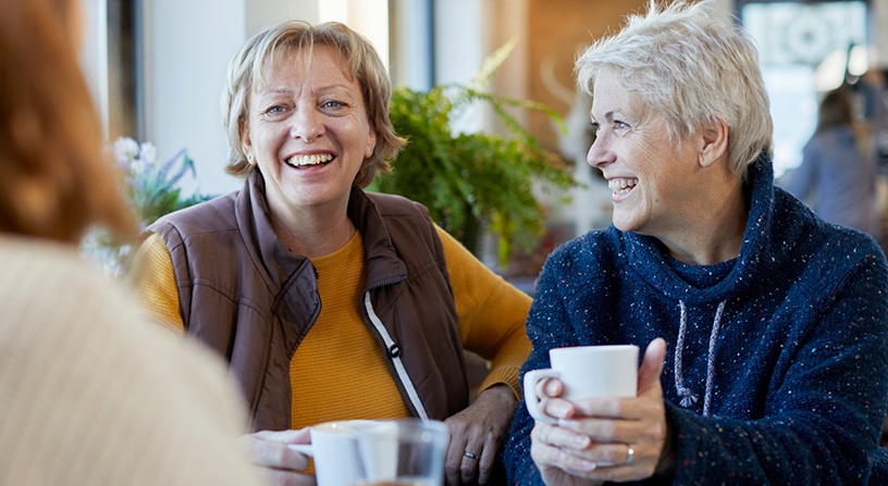 Two older ladies sharing a joke over a cuppa