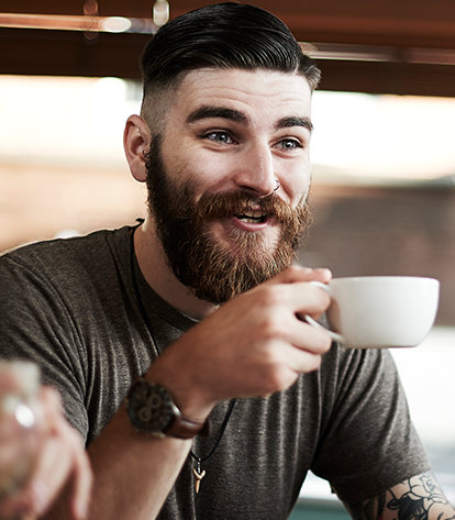 A young man smiling with a cup of coffee