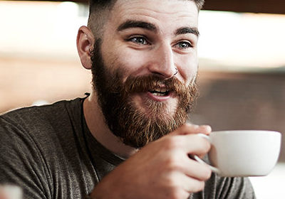 A young man smiling with a cup of coffee