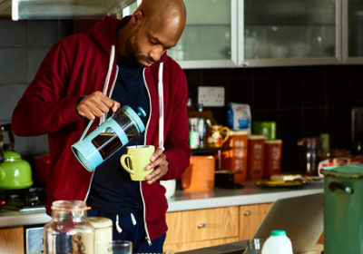 A young man pouring coffee in his kitchen 